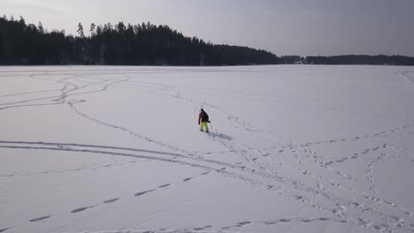 Amplia-Vista-Aérea-De-Un-Pescador-Solitario-Caminando-Sobre-Un-Lago-Congelado-En-Busca-Del-Lugar-Ideal-Para-Hundir-Un-Agujero