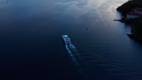 Ferry-sailing-into-the-sunset-passing-by-a-hotel-resort