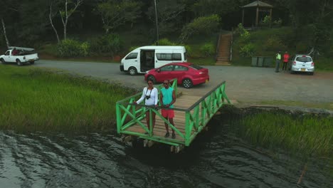 Aerail-view-of-a-couple-standing-at-the-edge-of-a-extinct-volcano-on-the-caribbean-island-of-Grenada,-Grand-Etang-Lake