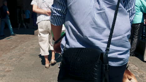 Chica-En-Cámara-Lenta-Caminando-Con-Su-Pequeño-Bulldog-Francés-En-La-Ciudad,-La-Mujer-Lleva-Un-Bolso-Y-Mantiene-Al-Perro-Atado