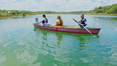 Slow-motion-of-three-girls-canoeing-on-the-lake-in-Chunyaxche,-Quintana-Roo,-Mexico