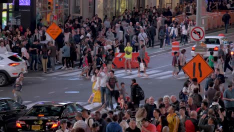 Toma-En-Cámara-Lenta-De-Personas-Cruzando-La-Calle-En-Un-Paso-De-Peatones-Y-Autos-Pasando-En-Una-Tarde-De-Verano-En-Times-Square-En-Manhattan,-Ciudad-De-Nueva-York,-Estados-Unidos