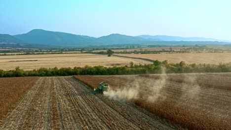 Luftaufnahme-Von-John-Deere-Mähdrescher-Bei-Der-Ernte-Von-Sonnenblumenfeldern-In-Bulgarien-Mit-Den-Hügeln-Von-Elena-Balkan-Im-Hintergrund-Und-Anhänger