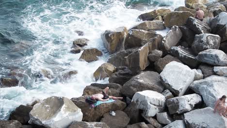 Touristen,-Die-Auf-Den-Felsen-Der-Küste-Von-Riomaggiore-Liegen