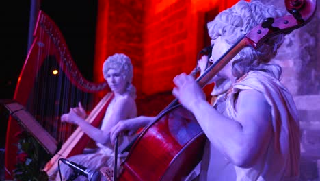 Two-women-playing-violin-and-harp-in-a-classical-theatre-musical-concert-dressed-as-angels-or-statues-outside-ancient-roman-amphitheatre-Aspendos,-Antalya