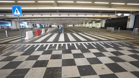 A-lone-man-wearing-a-backpack-in-the-deserted-airport-passenger-arrival-drop-off,-Brussels-Airport,-Belgium