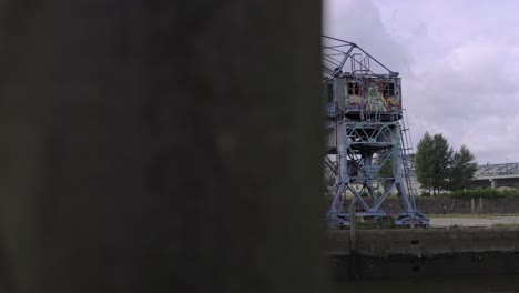 Pan-right-view-of-weathered-metal-crane-located-on-quay-against-overcast-sky-in-city