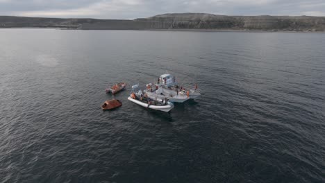 Seeleute-In-Ihren-Booten-Schwimmen-Im-Patagonischen-Meer-Nach-Einem-Nautischen-Training-Bei-Sonnenuntergang---Zeitlupe-Aus-Der-Luft