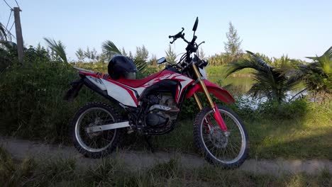 Motocross-motorbike-near-a-fishing-pond-on-the-shores-of-the-Thu-Bon-River,-Circle-around-shot