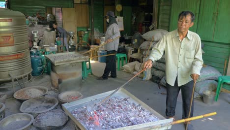 Thai-cookie-factory-workers-using-coal-and-metal-containers-for-baking,-slow-motion