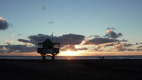 Vista-Icónica-De-La-Puesta-De-Sol-En-La-Torre-De-Salvavidas-En-La-Playa-De-Bethells-En-Auckland