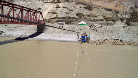 Young-man-showing-"-hang-loose-"-Hawaii-sign-before-he-slides-over-a-river-in-a-miner-cart-zip-line-suspended-on-a-rope