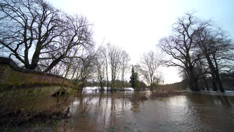 Flooded-bridge-showing-the-river-Bollin-in-Wilmslow,-Cheshire-after-heavy-rain-and-with-burst-banks-and-flooding-surrounding-area