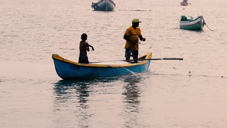 Un-Padre-Pescador-Enseñando-A-Su-Hijo-Métodos-Tradicionales-De-Pesca-En-Un-Pequeño-Bote-De-Madera-Cerca-De-Una-Playa-En-Aguas-Poco-Profundas-Y-Fondo-De-Video-De-Red-De-Pesca-En-Full-Hd-En-Mov