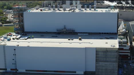 Vista-Aérea-Estática-De-Trabajadores-De-La-Construcción,-Trabajando-En-Altura-En-La-Azotea-De-Una-Central-Eléctrica