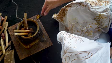 Woman-canting-to-create-unique-batik-motif-on-fabric-using-melted-wax,-Indonesia