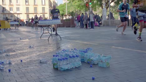 Corredores-De-Maratón-Corriendo-Pasan-Un-Puesto-De-Control-De-Agua,-Concepto-De-Residuos-Plásticos