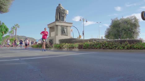 Marathonläufer-Laufen-Am-Monumento-Marqués-De-Heredia-In-Málaga,-Spanien,-Aus-Niedrigem-Winkel,-Echtzeitaufnahme-Vorbei