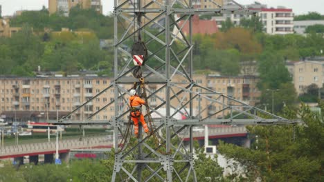 Der-Kletterer-Arbeitet-An-Einem-Hochspannungsmast,-Der-Für-Den-Transport-Mit-Einem-Kran-Vorbereitet-Wird