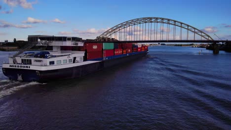 Vista-Aérea-De-Popa-Del-Buque-Portacontenedores-De-Missouri-Acercándose-Al-Puente-Sobre-El-Río-Noord