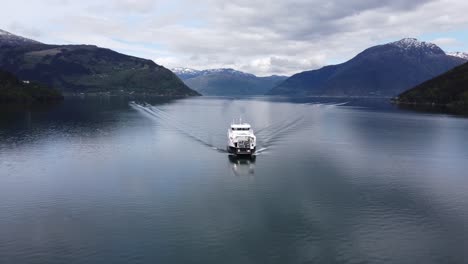 Norwegian-battery-powered-car-and-passenger-ferry-Kinsarvik-sailing-Hardangerfjorden-heading-for-Kinsarvik-village---Orbiting-aerial-from-bow-to-stern---Norway