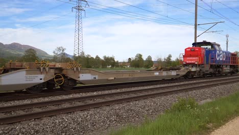 Static-shot-of-empty-swiss-cago-Rail-freight-transport-train-driving-on-tracks-in-Swiss-Countryside