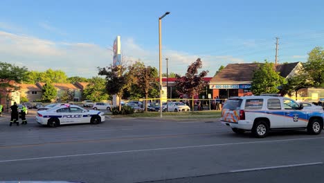 Police-officers-standing-behind-crime-scene-tape-beside-the-police-car