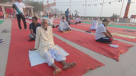 An-old-man-warming-up-at-Assi-Ghat-to-practice-group-yoga-organized-by-Subeh-Banaras-foundation-in-Varanasi,-India-on-09-March-2021