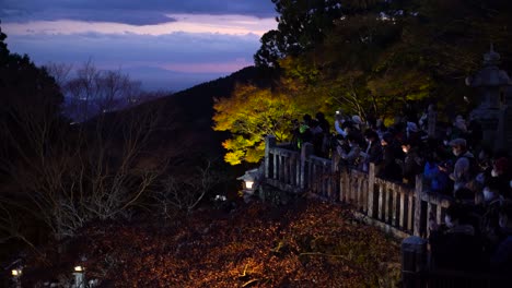 Densas-Multitudes-De-Espectadores-Con-Máscaras-Faciales-Tomando-Fotografías-De-Los-Colores-Otoñales-Por-La-Noche