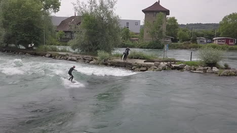 Surfista-Suizo-Se-Levanta-Sobre-Su-Tabla-De-Surf-En-La-Ola-Del-Río-Debajo-De-Weir