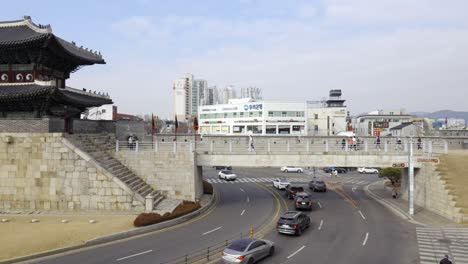 Viajeros-Que-Exploran-La-Famosa-Fortaleza-De-Hwaseong-Con-Tráfico-De-Automóviles-Bajo-El-Puente-Pedregoso