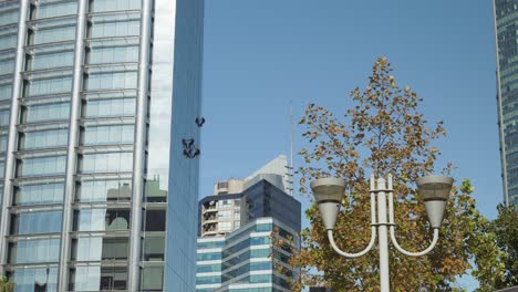 A-group-of-window-cleaners-hanging-from-a-modern-skyscraper-in-luxurious-area-at-daytime,-Santiago,-Chile