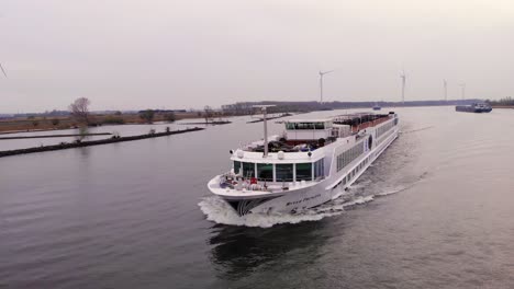 Luftaufnahme-Eines-Flusskreuzfahrtschiffs,-Das-Entlang-Der-Oude-Maas-Fährt-Und-An-Stillen-Windkraftanlagen-In-Barendrecht-Vorbeifährt