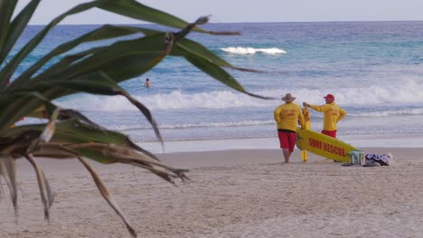 Socorristas-De-Servicio-De-Pie-En-La-Playa-Viendo-A-Los-Surfistas---South-Gorge-Beach-En-Verano-En-Point-Lookout,-North-Stradbroke-Island,-Australia