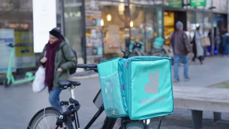 Bolsa-De-Comida-Deliveryoo-Abandonada-En-Bicicleta,-Ciclista-Recogiendo-El-Pedido-En-La-Tienda-De-Comestibles-Para-La-Entrega-Rápida---Bruselas,-Bélgica