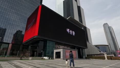 Coex-Artium-Y-El-Complejo-Del-Centro-De-Comercio-Mundial-En-Seúl,-Corea-Del-Sur,-Con-Una-Enorme-Pantalla-Curva-De-Publicidad-En-La-Entrada---Plano-General