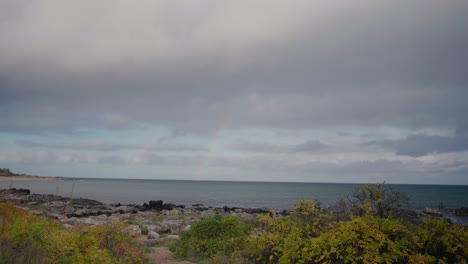 Autumn-Rainbow-By-The-Shore-of-Vårhallarna-in-South-Sweden-Österlen---Static-Wide-Shot