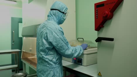 Laboratory-Specialists-In-Full-PPE-Closing-Lid-With-Samples-In-Box