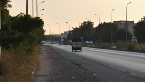 View-From-Hard-Shoulder-Of-Traffic-Going-Past-In-Karachi-With-Orange-Sunset-Sky