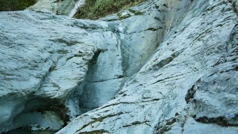 Woman-in-wetsuit-jumps-from-rock-ledge-into-deep-limestone-slot-canyon