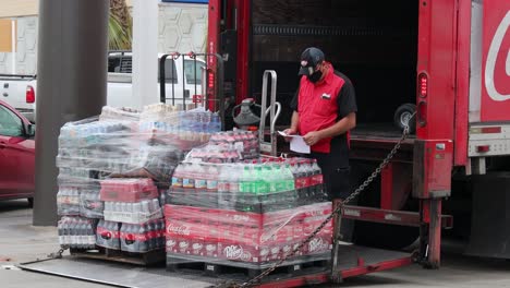 Mann-überprüft-Die-Rechnung-Und-Steht-Neben-Paletten-Mit-Cola-Produkten-Und-Einem-Lieferwagen-Mit-Coca-Cola-Logo