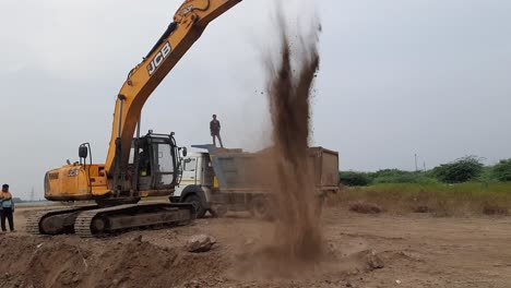 Up-close-view-of-an-excavator-digging-into-the-ground-and-loading-moorum-soil-into-the-dump-truck-on-construction-site