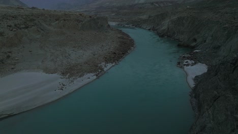 Antena-Sobre-El-Agua-Del-Río-De-Color-Turquesa-En-El-Valle-De-Hunza-En-Un-Día-Nublado-De-Mal-Humor-Oscuro