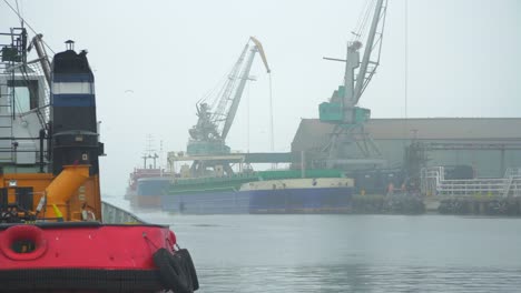 Grúas-Portuarias-Cargando-Un-Buque-De-Carga-Seca-En-El-Puerto-De-Liepaja-En-Un-Día-Brumoso,-Plano-Medio