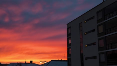 Timelapse-De-4k-De-Una-Colorida-Puesta-De-Sol-Que-Muestra-Fuertes-Colores-Rojos-En-El-Cielo-Con-Reflejos-En-Las-Ventanas-De-Un-Nuevo-Edificio-De-Apartamentos