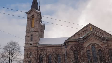 Saint-Charle's-church-in-Tallinn-standing-tall-with-dramatic-white-and-blue-sky,-with-some-snow-on-the-roof