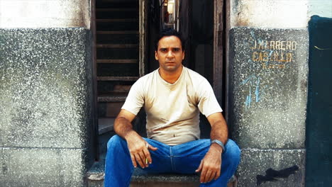 A-motion-portrait-of-a-middle-aged,-rough-looking-Cuban-man-sitting-down-to-have-a-cigarette-break-in-Havana