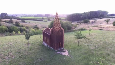 A-drone-shot-flying-upwards-and-slowly-panning-down,-focusing-on-a-see-through-church