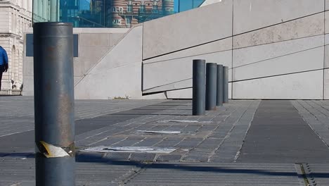 Low-angle-view-of-electric-security-bollards-lowering-as-vehicle-passes-across---peoples-feet-walking-past