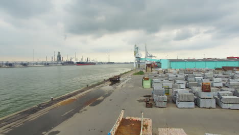 Drone-footage-in-the-port-of-Antwerp,-Scheldt-river,-cargo-ships,-machinery,-granite-blocks,-far-view-from-the-nuclear-power-plant-in-Doel